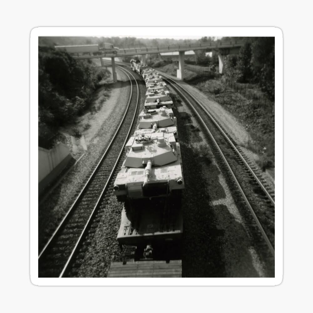 Black and white photograph looking down over a long armored train traveling between parallel tracks.